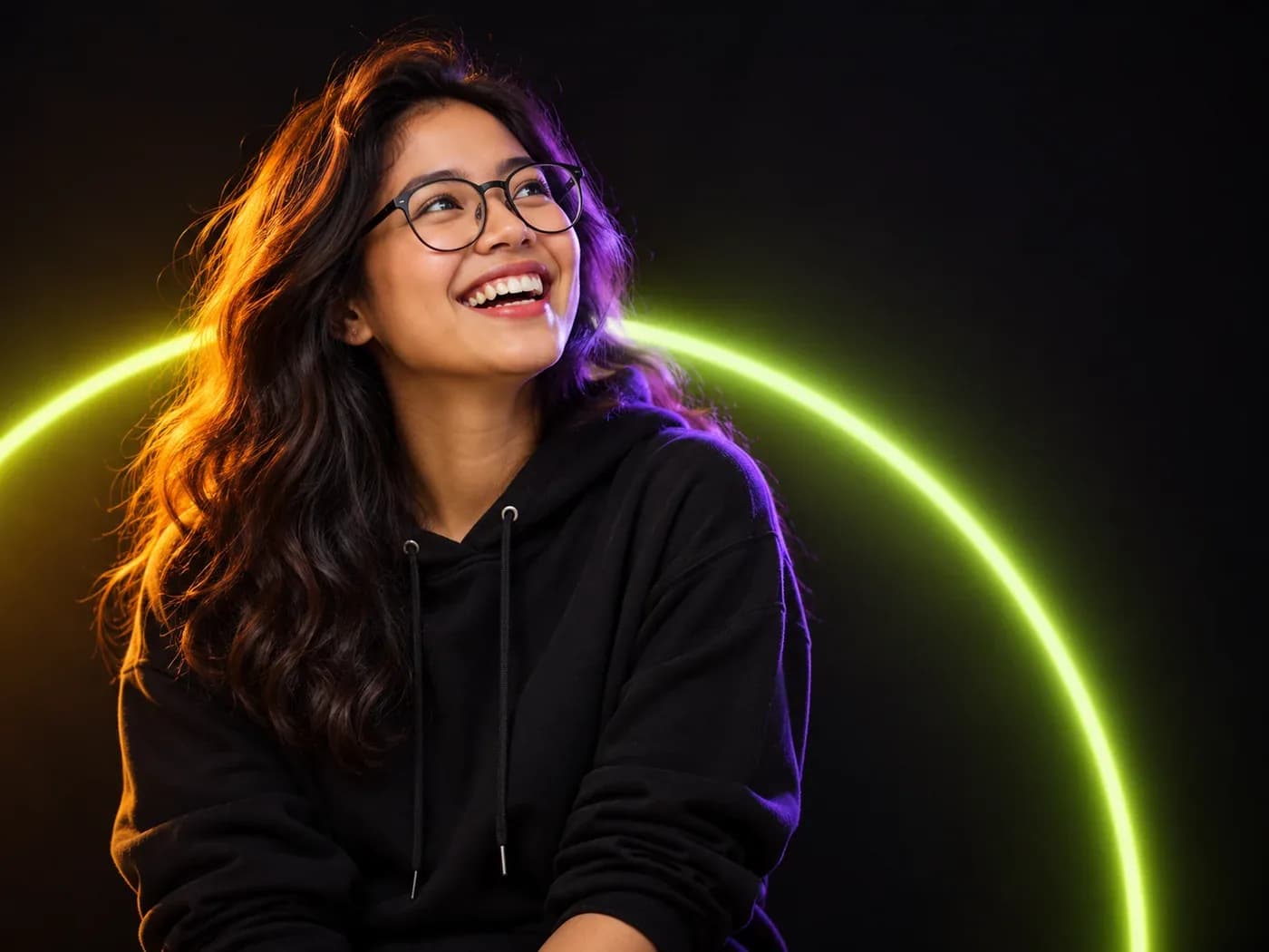 A smiling entrepreneur in glasses and a black hoodie, surrounded by lime and violet light